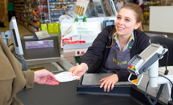 Waitrose cashier handing a customer a coupon
